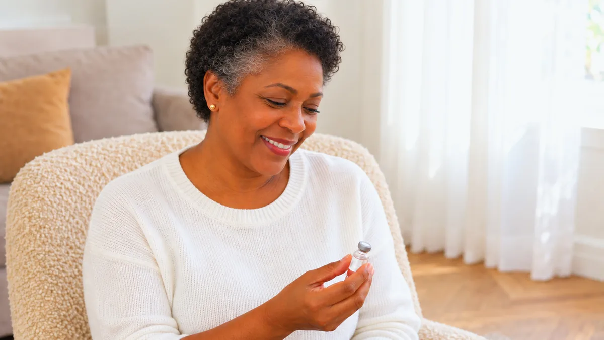 A smiling woman checking her injection vial at home